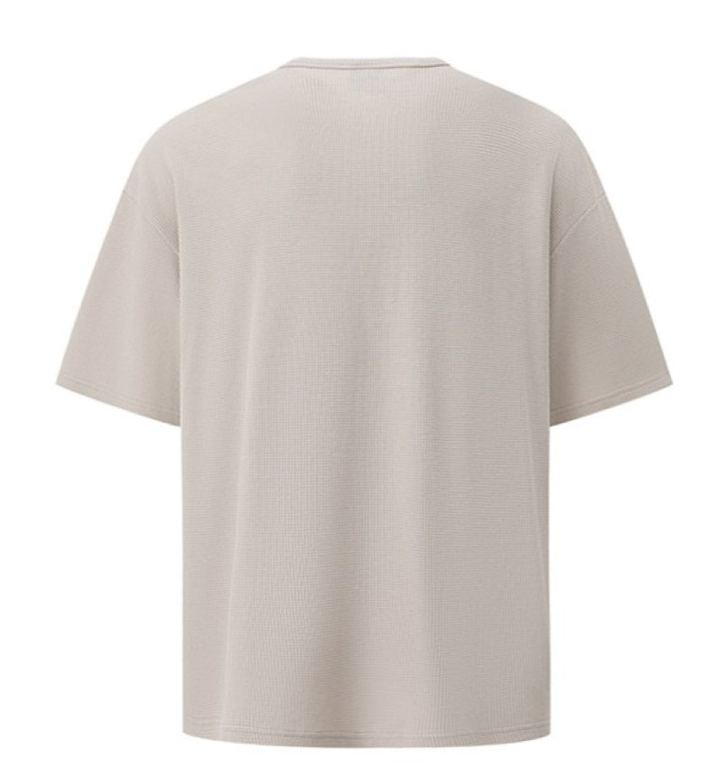 カーキのヘンリーネックワッフル半袖Tシャツを真後ろから捉えた、平置きの全体写真。
