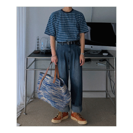 ブルーのストライプTシャツをデニムパンツにタックインし、編み込みの大きなトートバッグを持って佇む男性の全身フロントカット