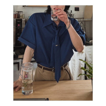 ネクタイを締めたダークブルーの半袖シャツを着用し、キッチンカウンターで水を飲む男性のスタイリッシュなカット