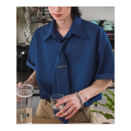 ネクタイを締めたダークブルーの半袖シャツを着用し、キッチンカウンターで水を飲む男性のスタイリッシュなカット