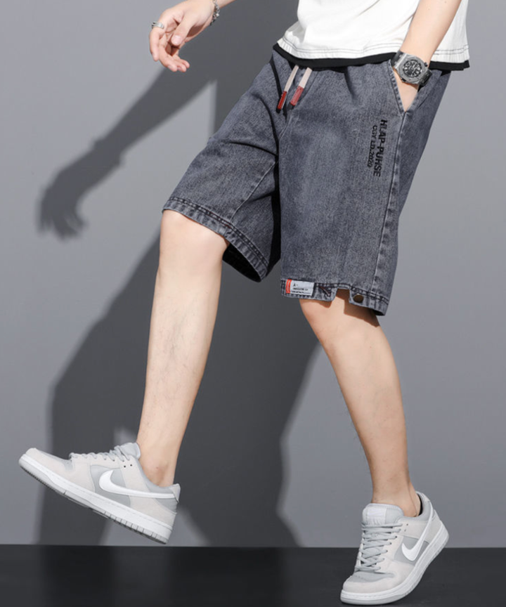 ウォッシュ加工が施されたグレーのメンズデニムハーフパンツを着用し、真横を向いて歩いている男性の全身写真。