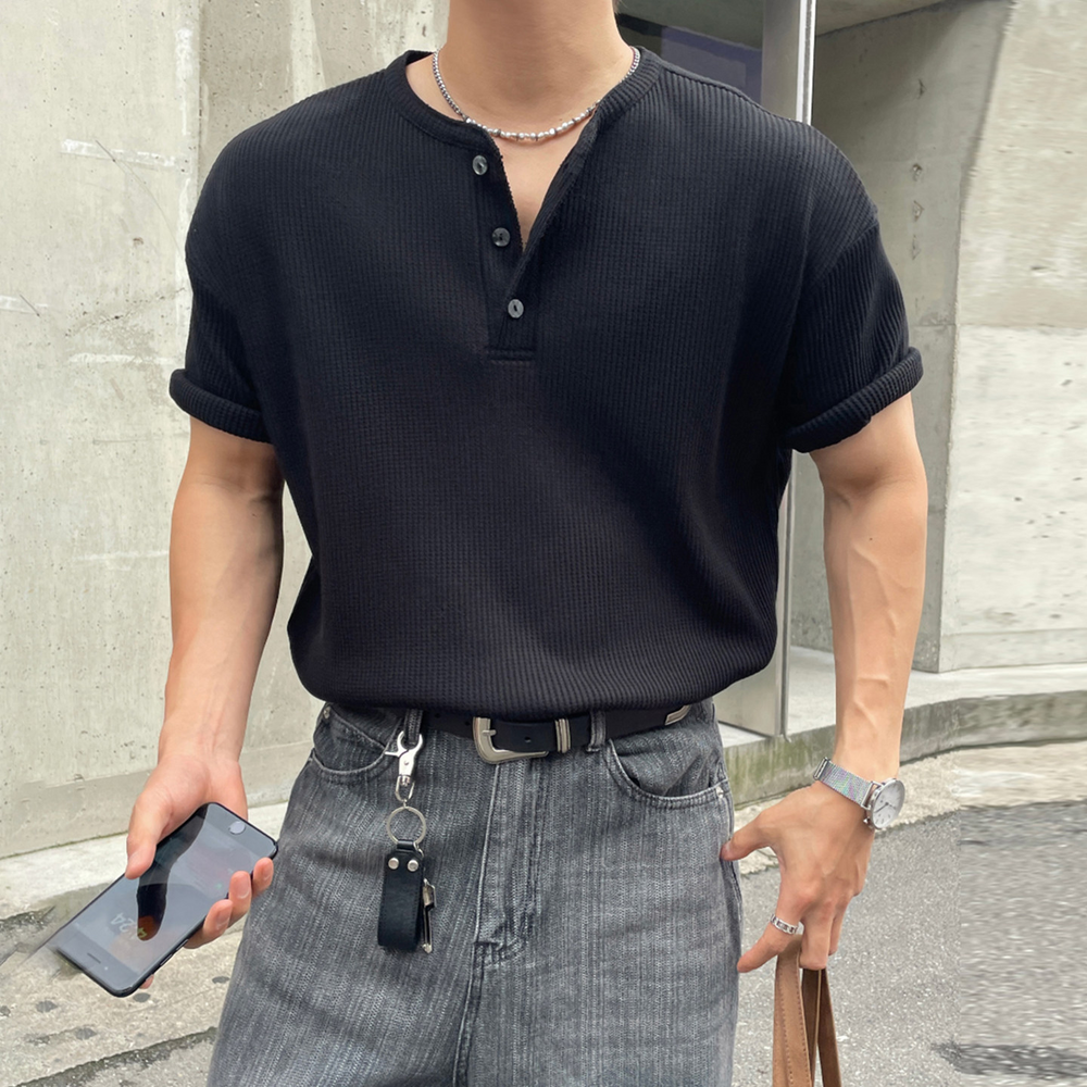 黒のワッフル生地の半袖ヘンリーネックTシャツを着用し、グレーのデニムパンツにタックインした男性のスタイリング