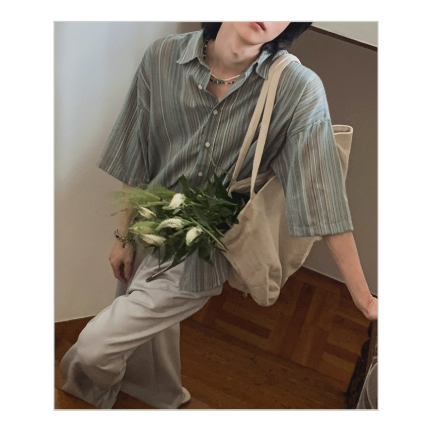 ストライプ半袖シャツにライトグレーのワイドパンツを合わせ、階段でポーズをとる男性の全身カット