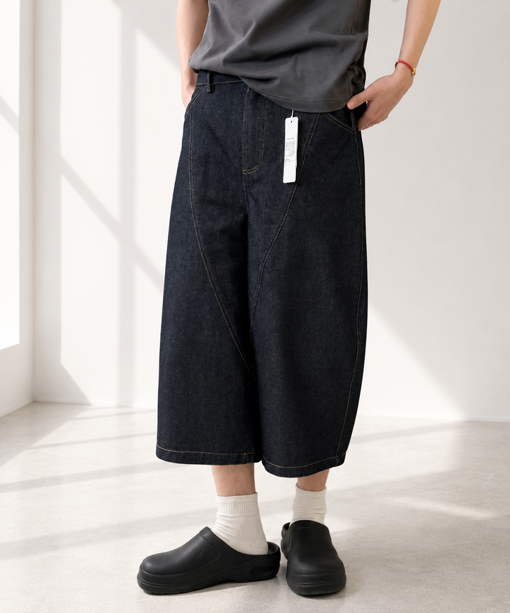 クロップドバレルレッグデニムパンツを着用し、白ソックスと黒のサボサンダルを履いた男性の斜めからの足元コーディネート。