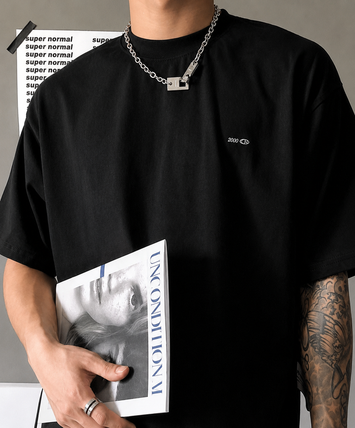 黒のTシャツを着用した男性が、洋書（雑誌）を片手に持っているスタイリングカット。
