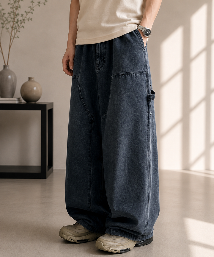 ブラックのワイドパネルデニムパンツを着用し、室内に立っている人物の斜め前からのカット。
