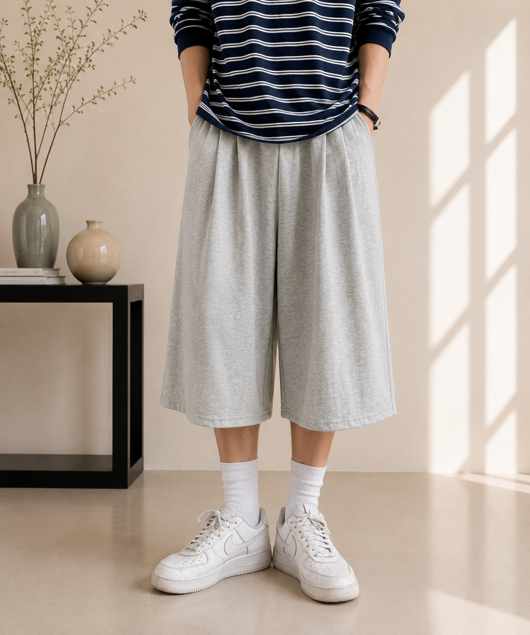 フロントにタックが入ったグレーのワイドイージーパンツのシルエットが際立つ、人物の腰から下の正面アップ写真。