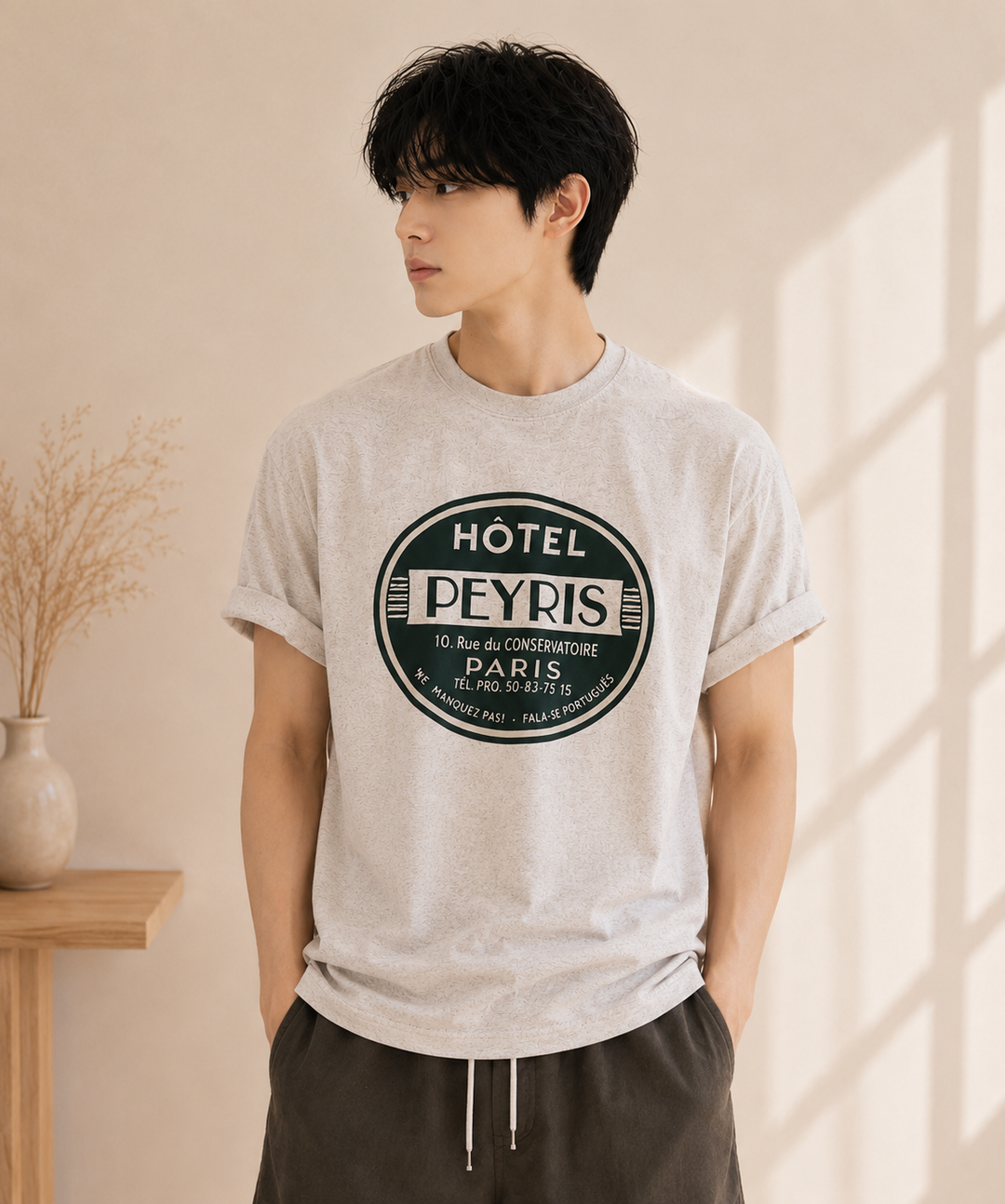 グレーのサークルロゴTシャツにオリーブグリーンのパンツを合わせているている男性。
