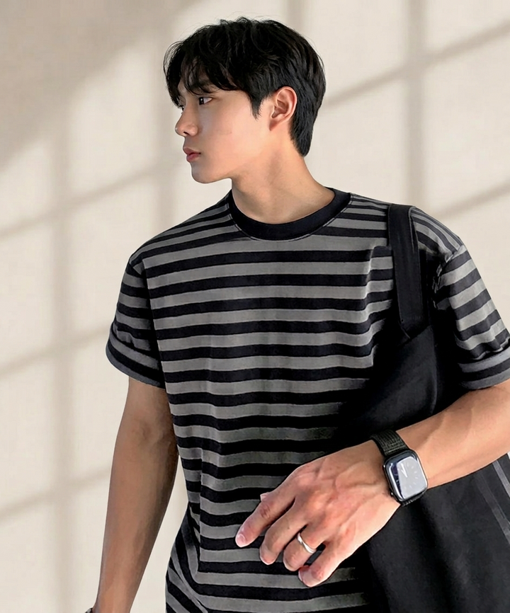 ボーダーTシャツの首元から胸元、手元までを斜めから捉えたアップカット。黒いスマートウォッチと指先のシンプルなシルバーリングが、フェード感のあるボーダー柄に映えるスタイル。