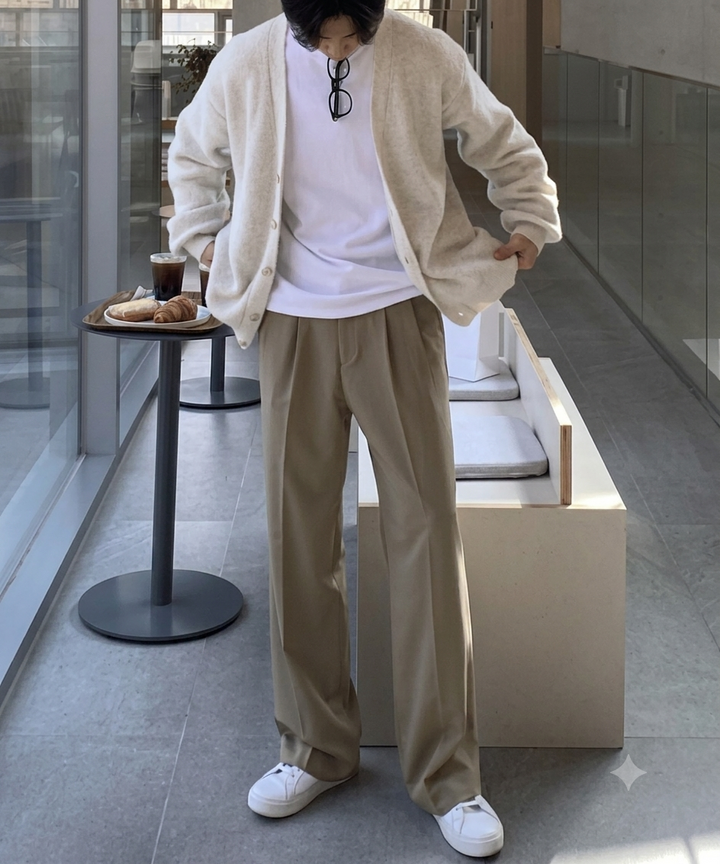 ダークベージュのワイドパンツに白いスニーカーを合わせ、オフホワイトのカーディガンを合わせたコーディネート。