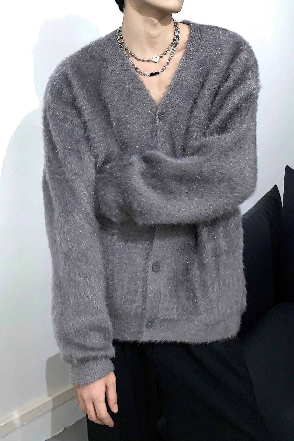 細かなラメが輝くグレーのシャギーVネックカーディガンを着用し、腕を組んだ男性の正面カット。