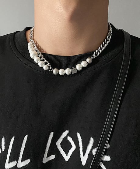 グラフィックがプリントされた黒のTシャツの首元に、ホワイトパールと喜平チェーンのアシンメトリーな組み合わせが映えるネックレスの着用アップカット
