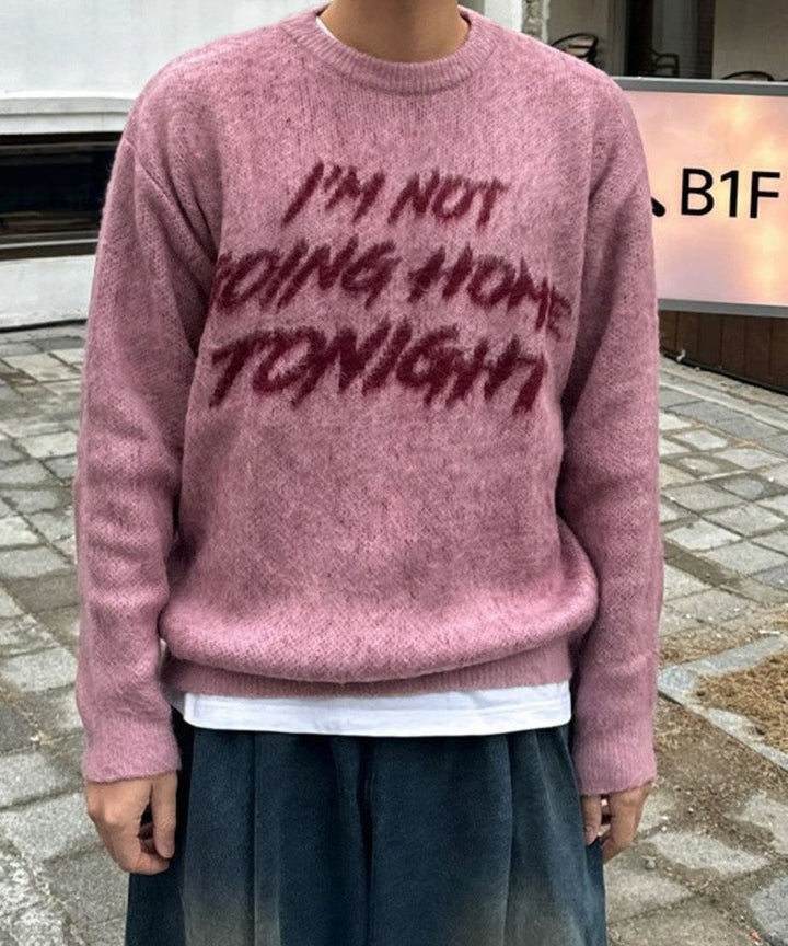 ピンクのシャギーブークレニットをスッキリと着こなす男性のバストアップカット。