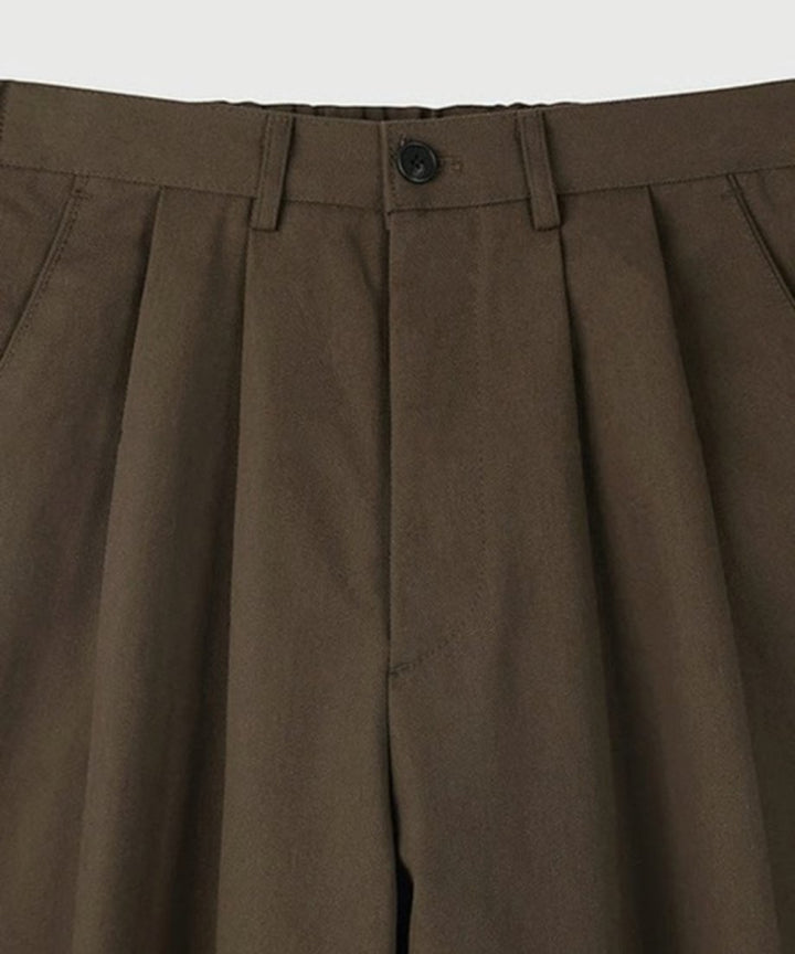 白背景に置かれた、ブラウンのツータックワイドスラックスの単体商品置き画カット。