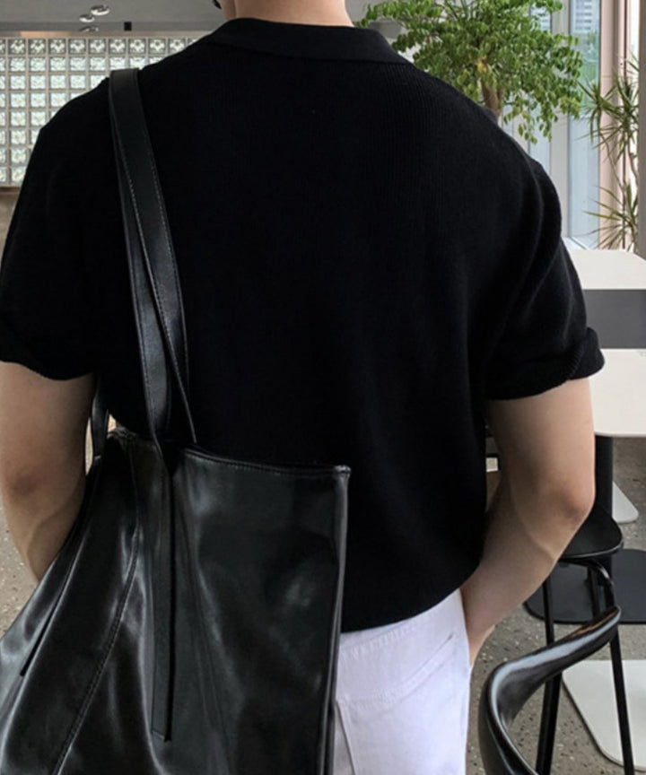 ブラックのハーフジップニットポロに黒のレザートートバッグを肩掛けした、シンプルで男らしい後ろ姿のバックカット。