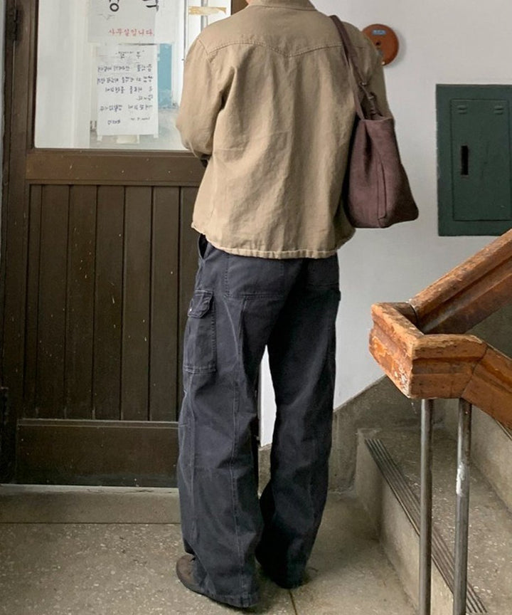 カーキブラウンのシャツを着用した人物の、斜め後ろからの後ろ姿を捉えたバックスタイル写真。