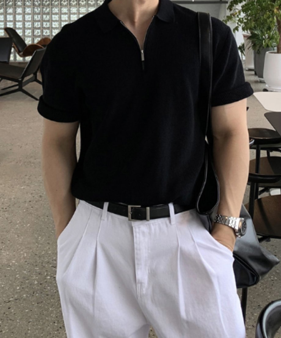 ブラックのハーフジップサマーニットポロに白のタックパンツ、黒のレザーベルトを合わせた、シックで洗練されたモノトーンのメンズコーディネートカット。
