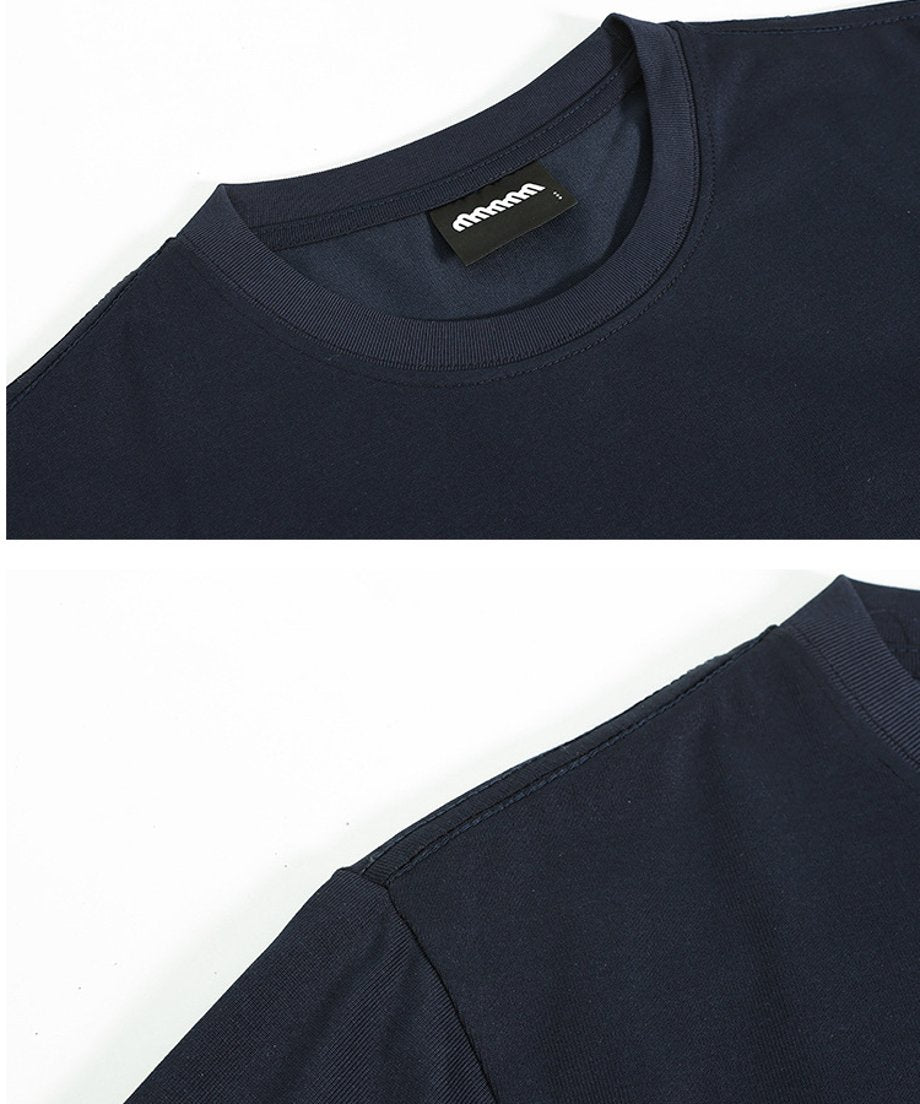 ネイビーのTシャツの首元クルーネック部分と、肩・袖付けの丁寧なステッチがわかるクローズアップ写真。