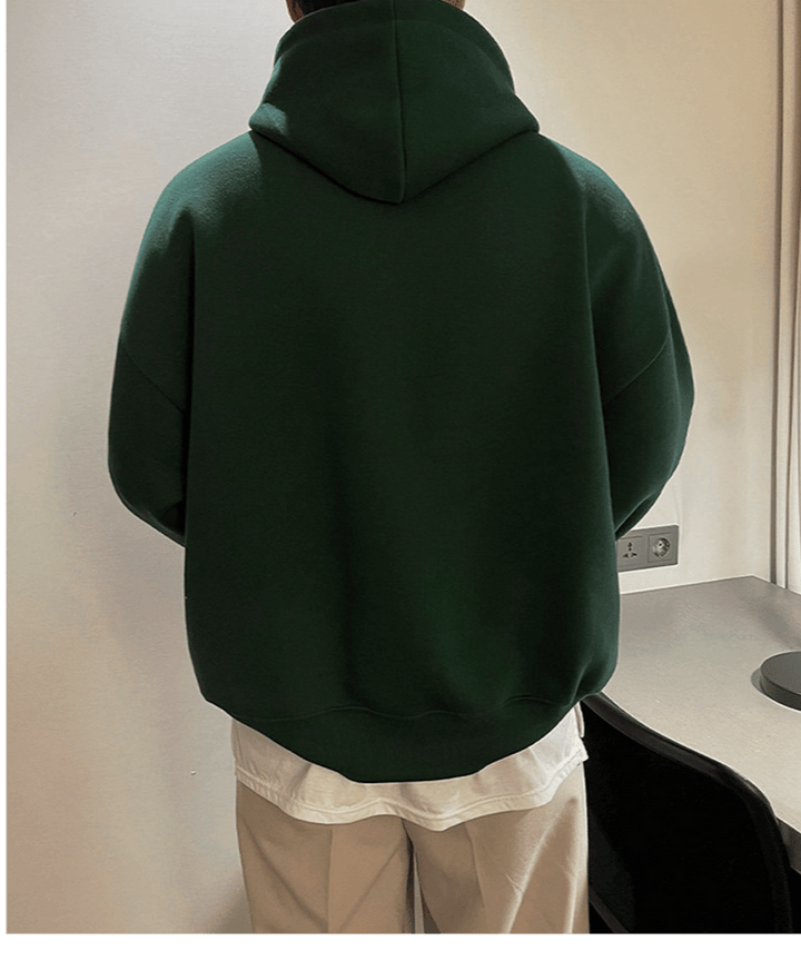 ダークグリーンのオーバーサイズパーカーを着用した男性の後ろ姿のカット。