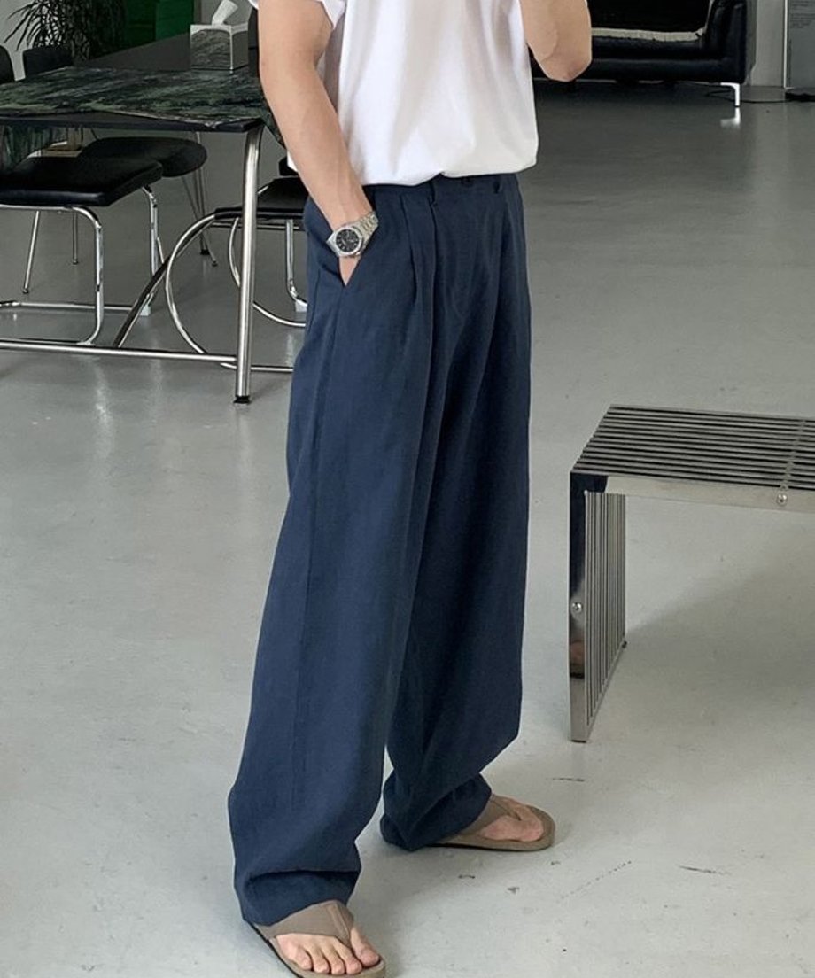 白のTシャツにロイヤルブルーのツータックワイドパンツを合わせ、ポケットに手を入れて立つ男性の斜め前からの姿。