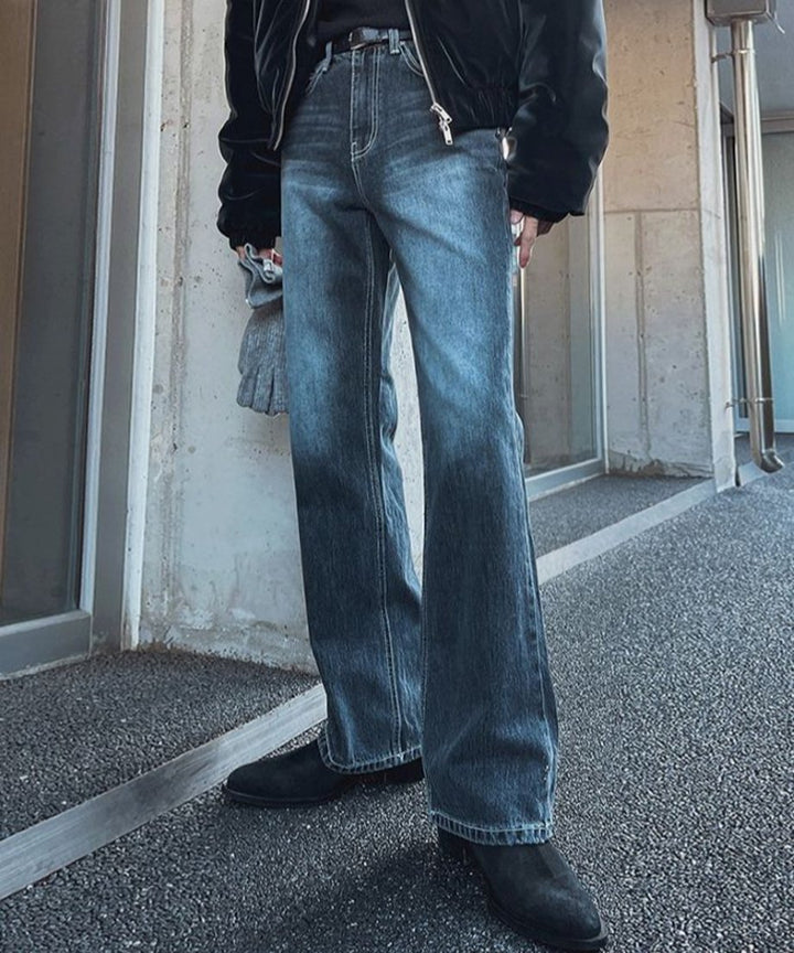 ウォッシュドブルーのワイドデニムパンツを穿き、手にグレーの手袋を持った人物の、斜めフロントからのスタイリングカット。