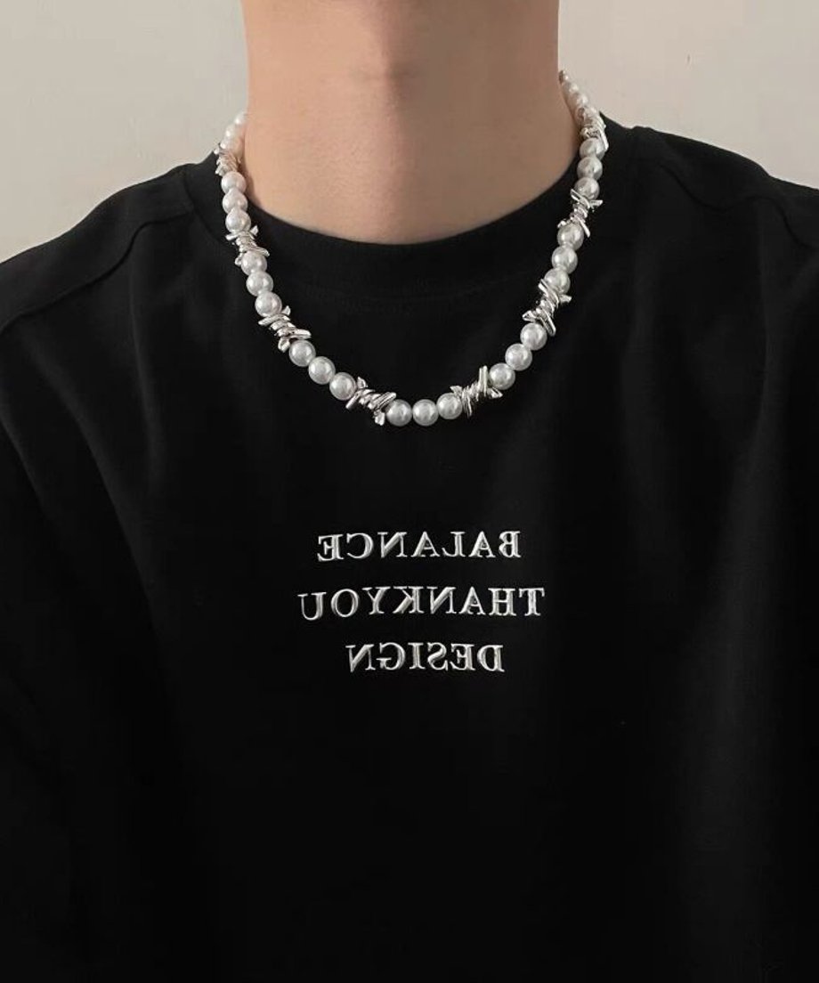 黒のロゴTシャツに有刺鉄線モチーフのパールネックレスを着用したメンズの胸元画像