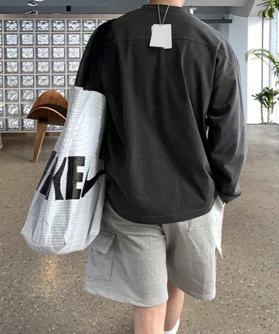 ウォッシュ加工が施されたアイアングレーの長袖Tシャツに、ライトグレーのカーゴハーフパンツを合わせた男性の後ろ姿