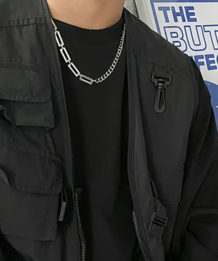 黒いTシャツとタクティカルベストを合わせたストリートコーデの首元に、シャープなシルバーのコンビチェーンネックレスが輝くアップカット