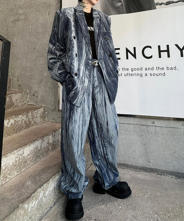 独特の縦シワと光沢が特徴的なグレーのクラッシュベロアセットアップを着用した男性の全身カット。