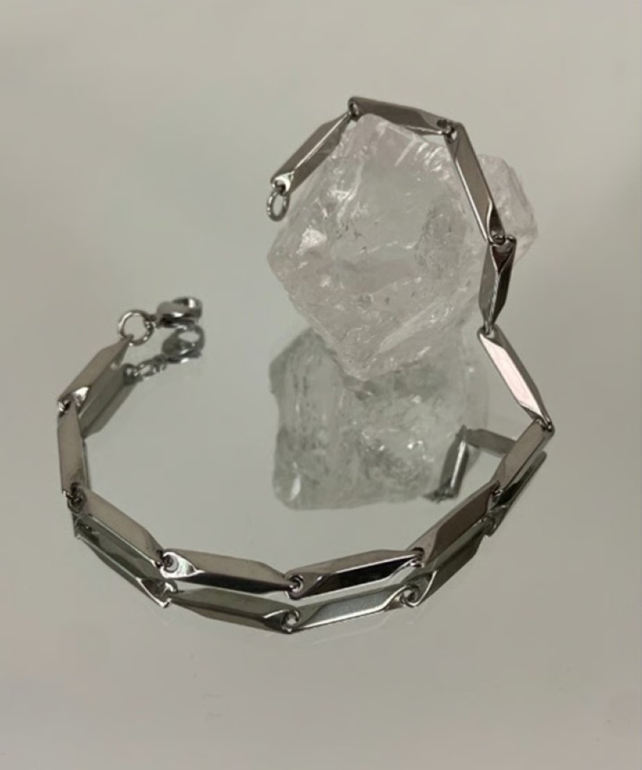 ミラーの上に置かれたブレスレットと透明な水晶の物撮り。
