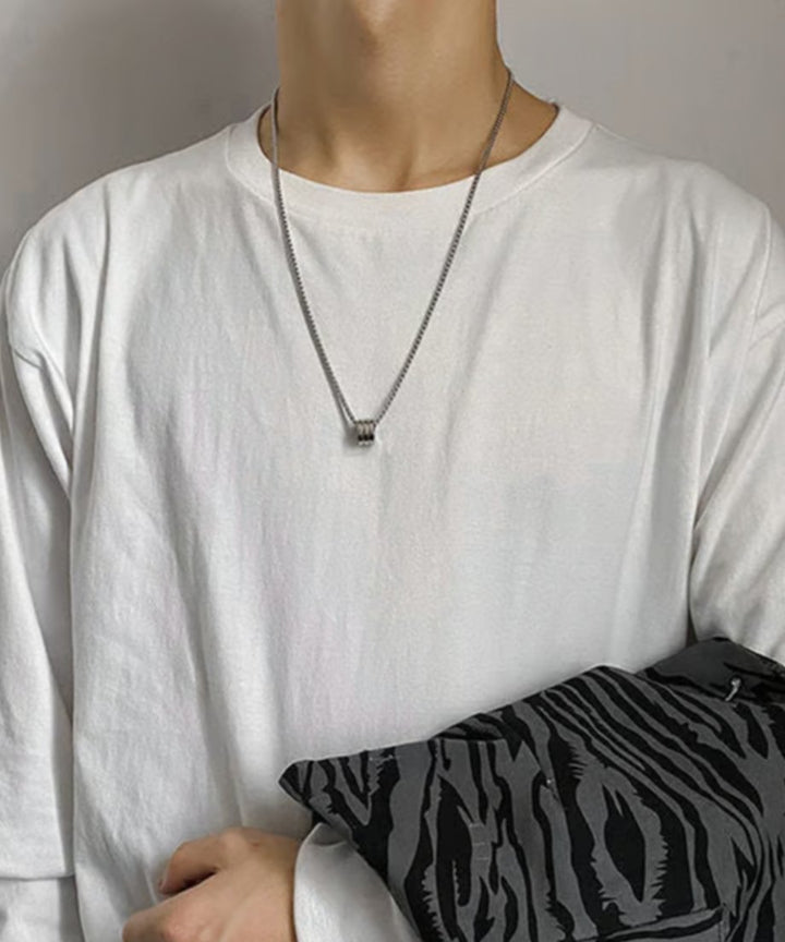 クリーンな白のロングスリーブTシャツの胸元にシルバーネックレスをシンプルに合わせ、ゼブラ柄の小物を手にしたキレイめカジュアルな着用カット。