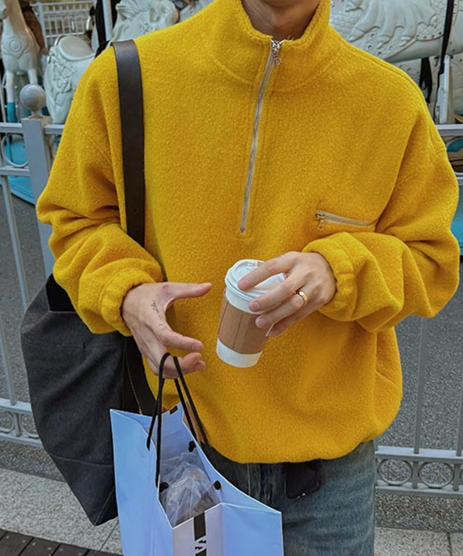 マスタードイエローのハーフジップフリースを着用した男性のバストアップカット。ジーンズを合わせている。