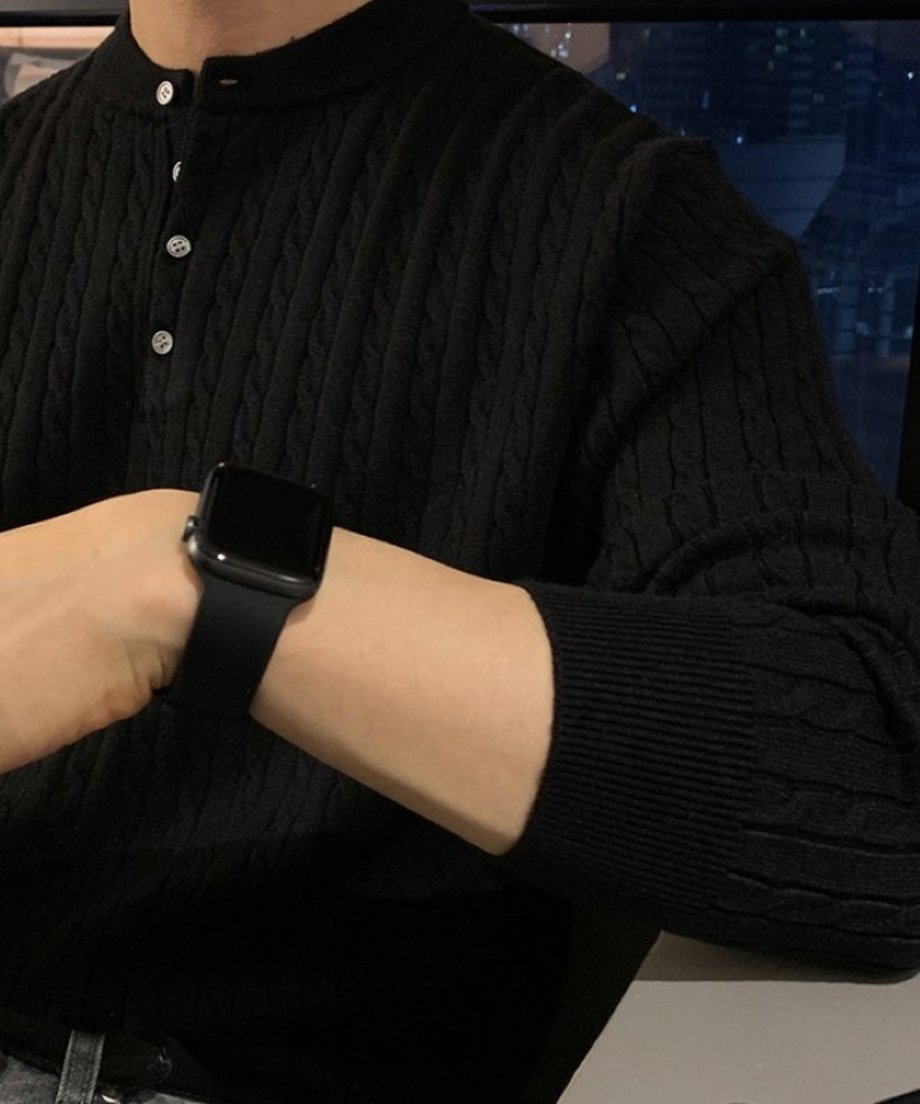 ブラックのヘンリーネックケーブルニットの首元と袖口のアップ。左腕に黒のスマートウォッチを着用している男性のカット。