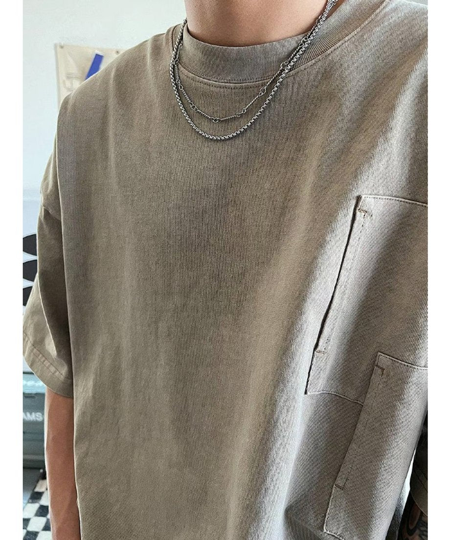 ルーズシルエットのTシャツに合わせた、胸元から肩のラインにかけてのチェーンの立体感やドロップショルダーとのバランスを捉えた斜めからのカット。