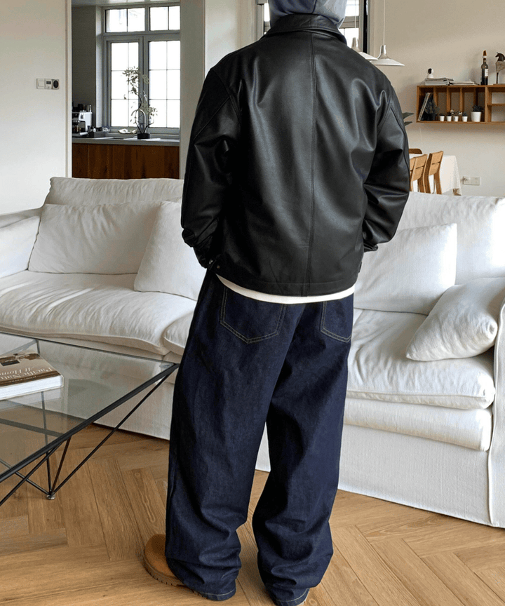 黒のレザージャケットとネイビーのワイドデニムパンツを着用した人物の、後ろ姿を捉えたスタイリング写真。