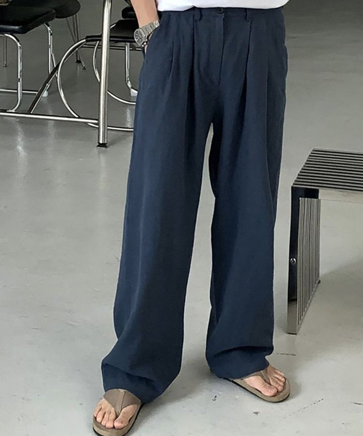ロイヤルブルーのツータックワイドパンツとトングサンダルを着用した男性の足元のアップ。
