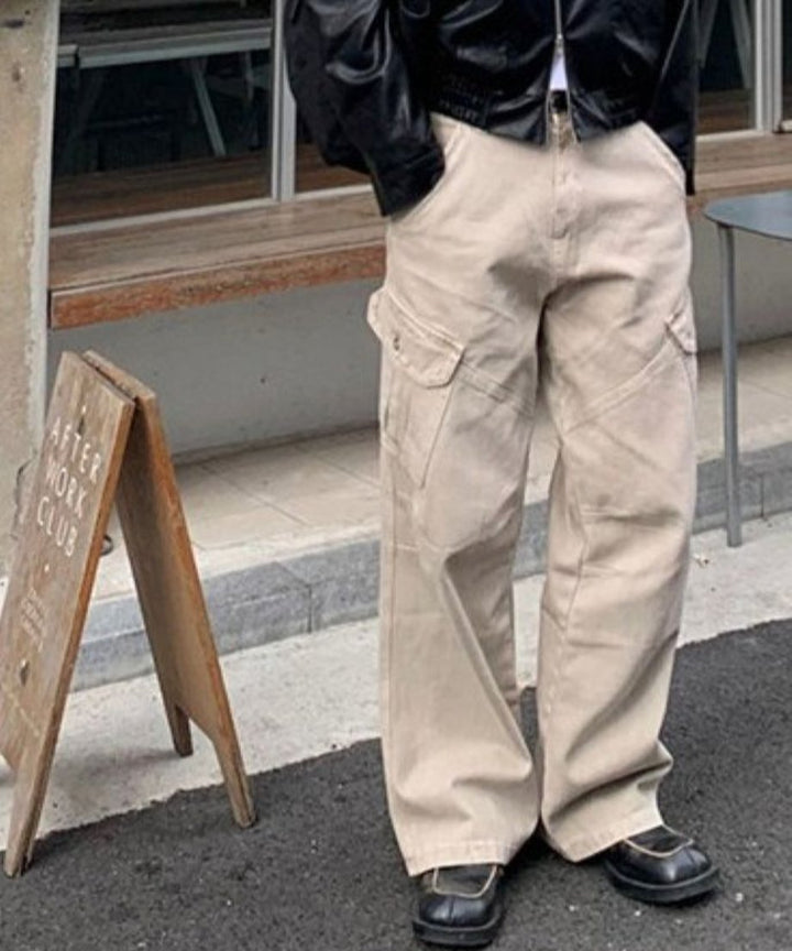 レザージャケットを羽織り、カーキのワイドカーゴパンツを穿いた人物の、腰から足元を斜めから捉えた写真。