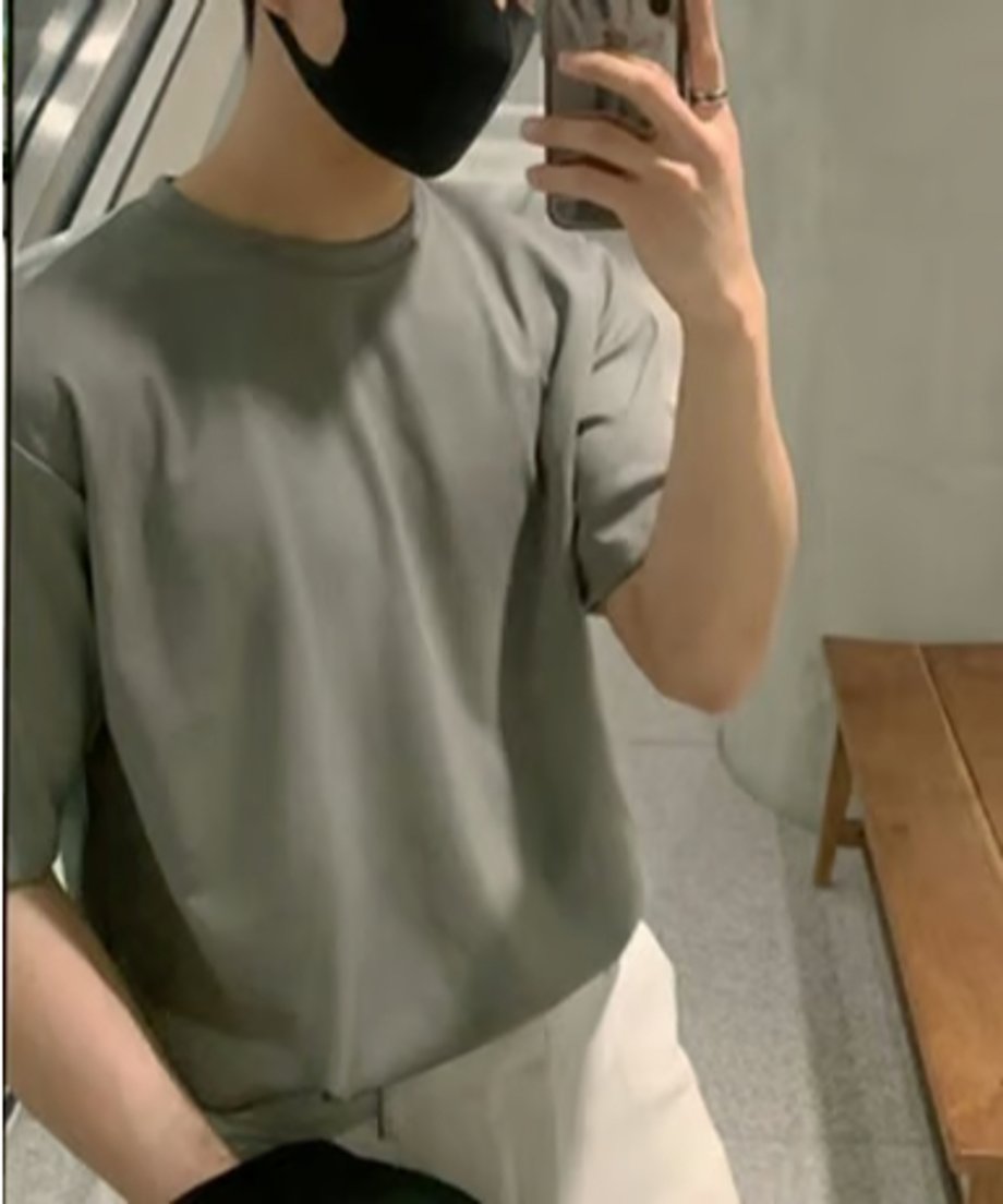 ミントグリーンのクルーネックTシャツにホワイトのボトムスを合わせ、鏡越しに自撮りをする男性の姿。