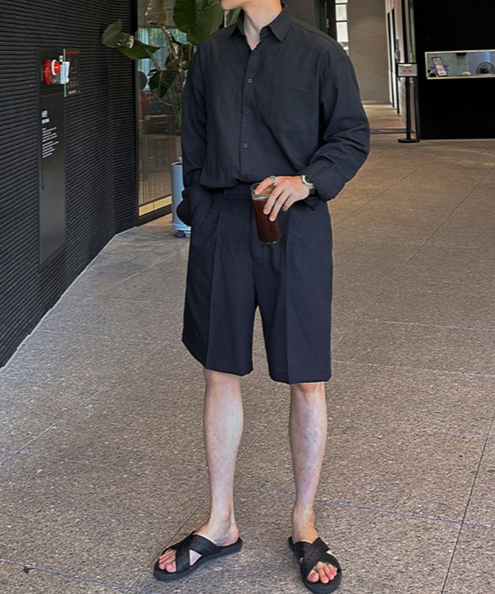 ブラックのリネン混長袖シャツにハーフパンツを合わせtた男性。