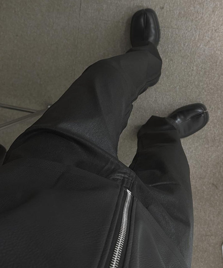 黒のフェイクレザージャケットと黒のスリムパンツ、つま先が分かれた黒のタビシューズを合わせた男性の足元を見下ろしたアングル写真。