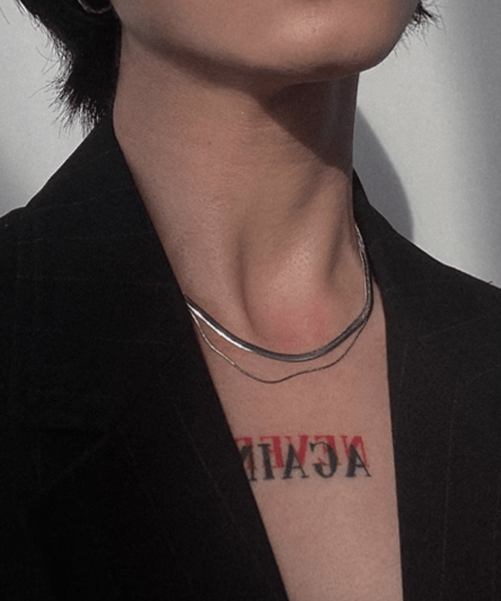 黒いストライプジャケットの襟元から覗く首元に、美しい艶のあるスネークチェーンと極細チェーンの2連ネックレスを着用した、モードな雰囲気のスタイリングカット。