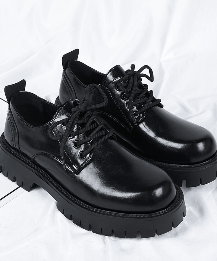 厚底オックスフォードシューズを斜め上の角度から捉え、綺麗に結ばれたブラックの靴紐と、光を反射するアッパーの高級感を綺麗に写した商品写真。
