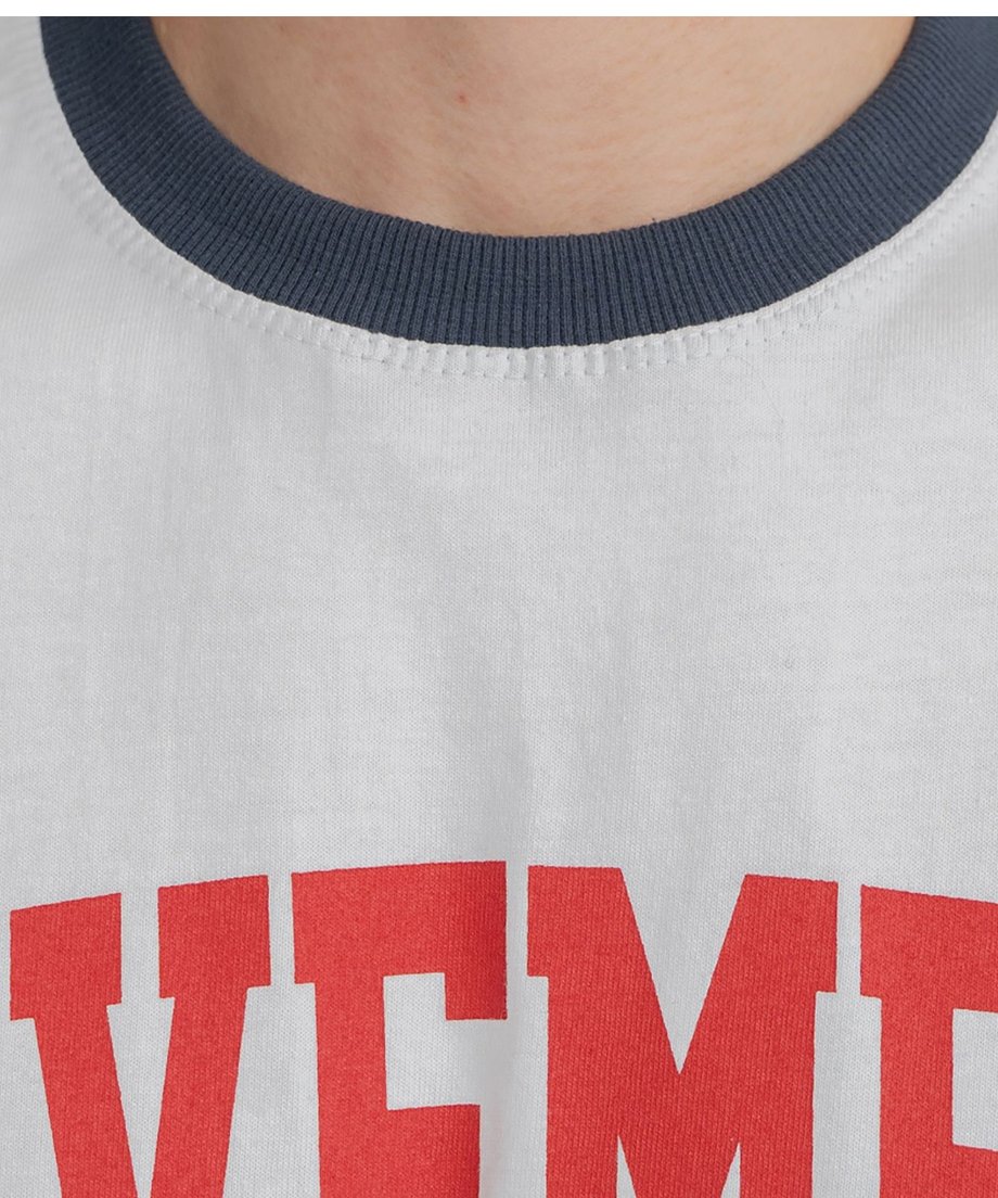 ホワイト地にネイビーのリブが映える、リンガーTシャツの丸首部分と赤のカレッジロゴプリントを捉えた生地の風合いクローズアップ写真。