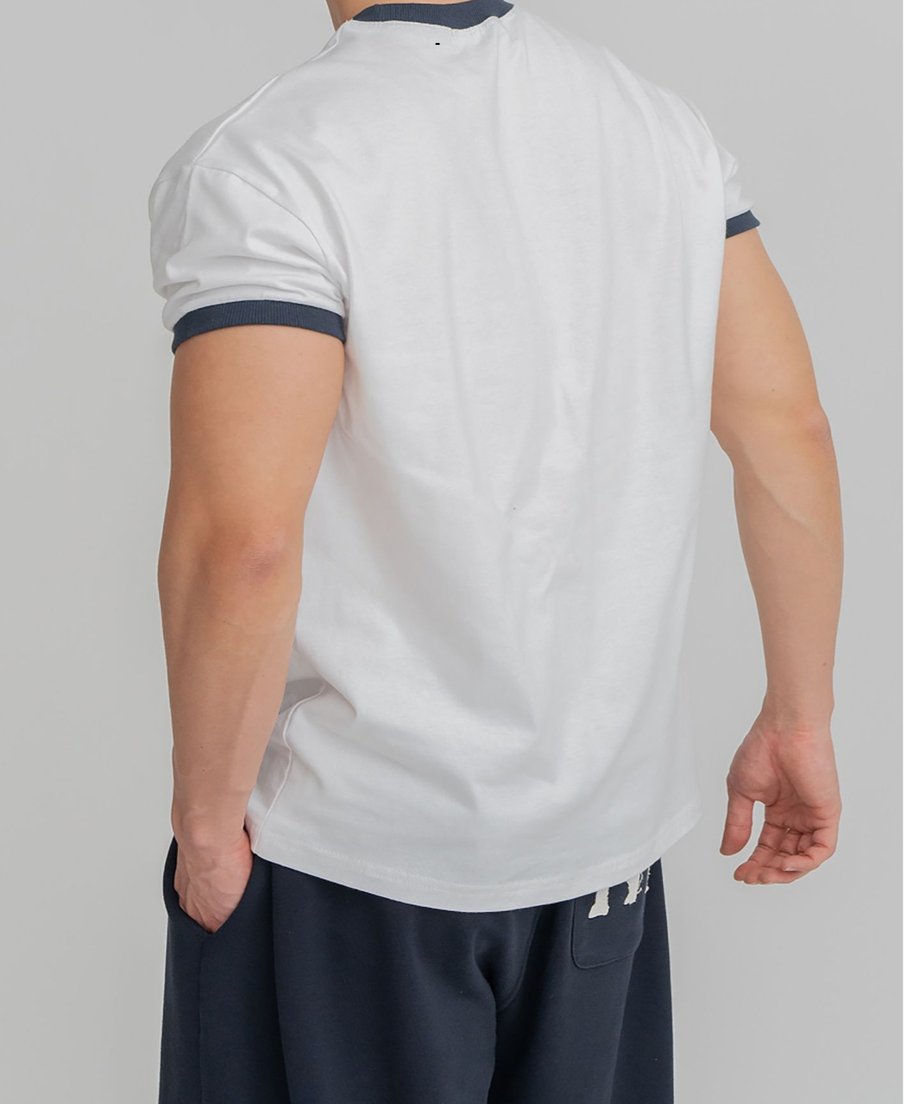 ホワイトのリンガーTシャツを着用し、両手をバックポケットに入れて後ろを振り返る男性の後ろ姿カット。