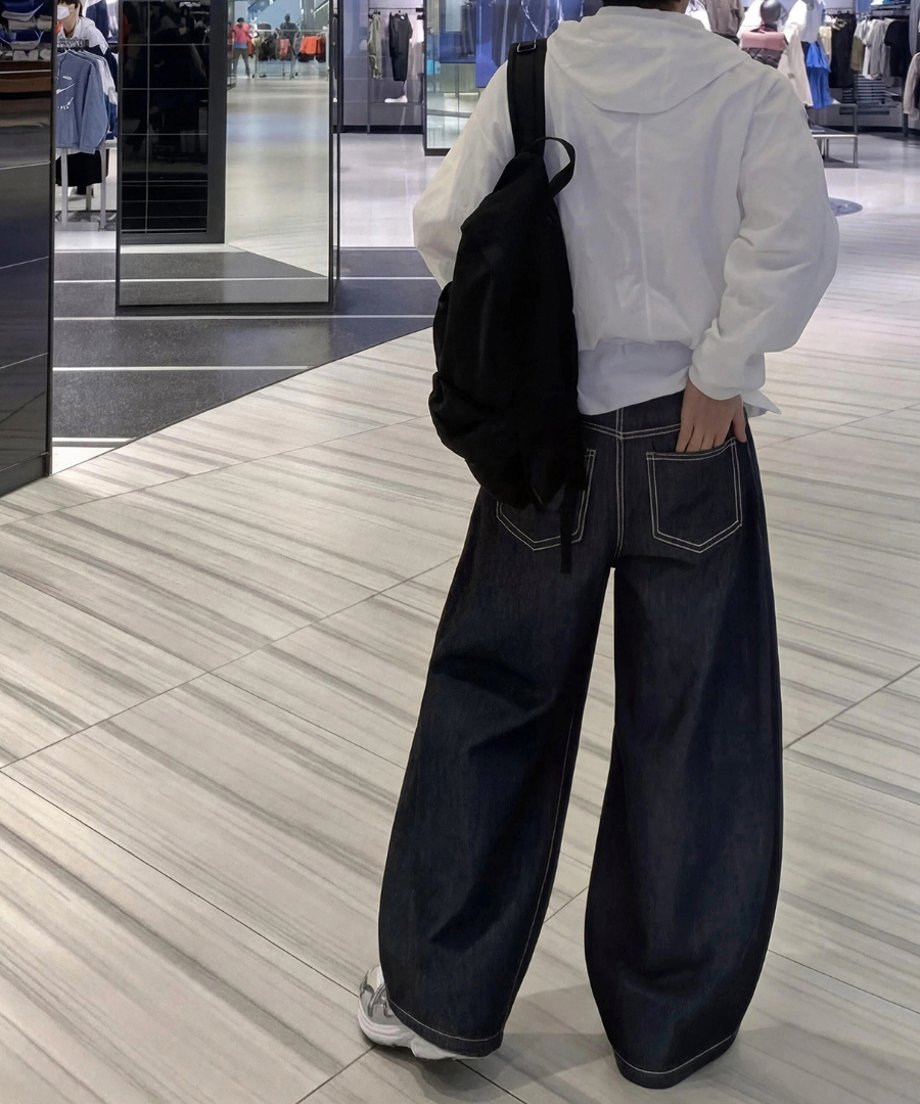 リュックを背負いポケットに手を入れながら歩く人物を、斜め後ろから捉えた写真。