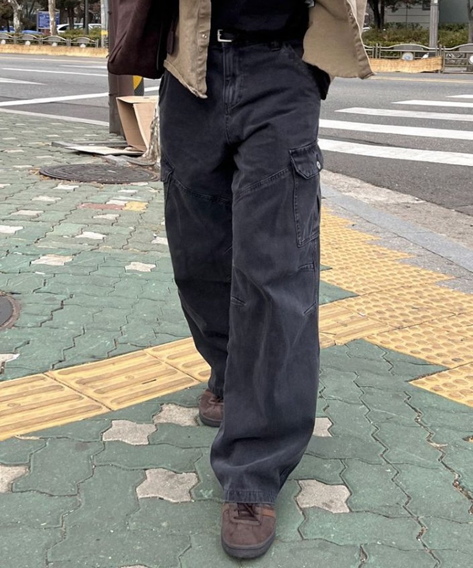 カーキブラウンのシャツを羽織った人物が、ブラックのワイドカーゴバギーパンツを穿いて歩いている、腰から足元にかけてのフロントカット。