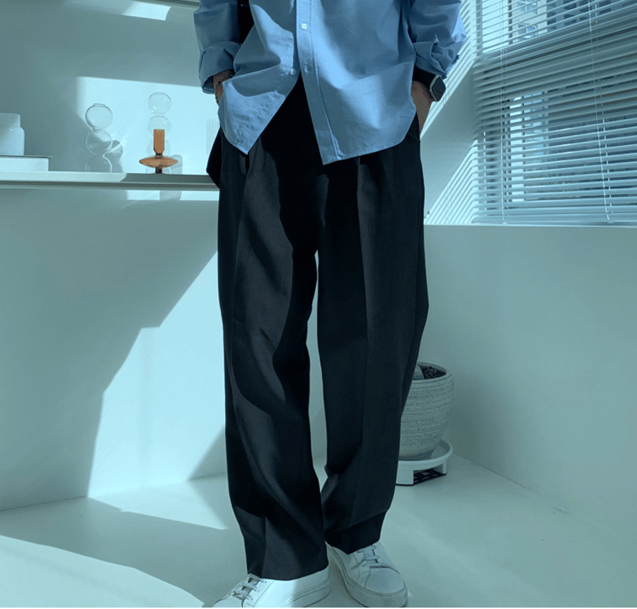 ブラックのワンタックワイドスラックスにブルーシャツを合わせた男性のフロント全身カット。