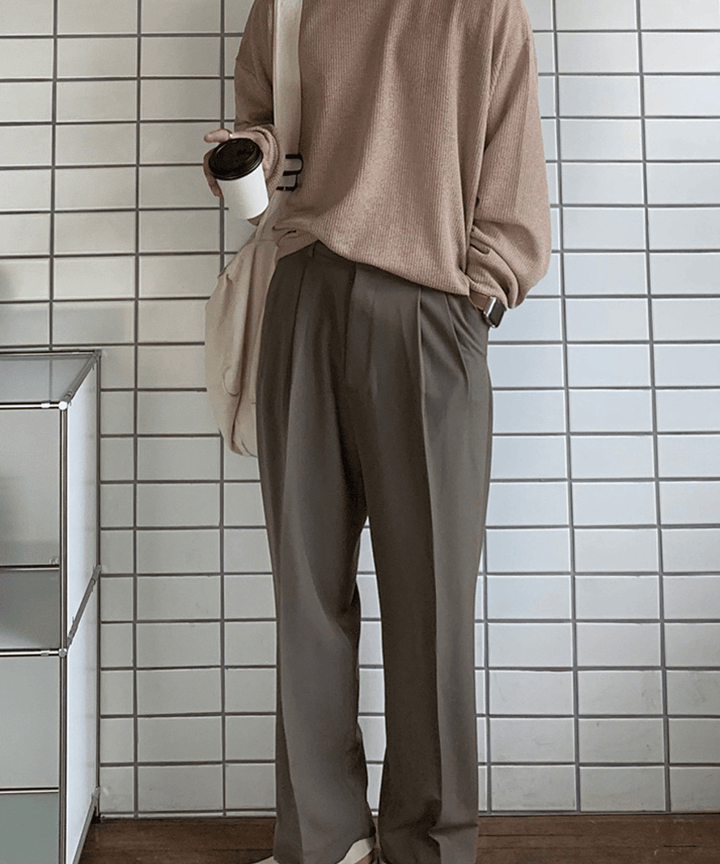 ベージュのクルーネックカットソーに、ダークブラウンのワンタックワイドスラックスを合わせた男性のフロントカット。