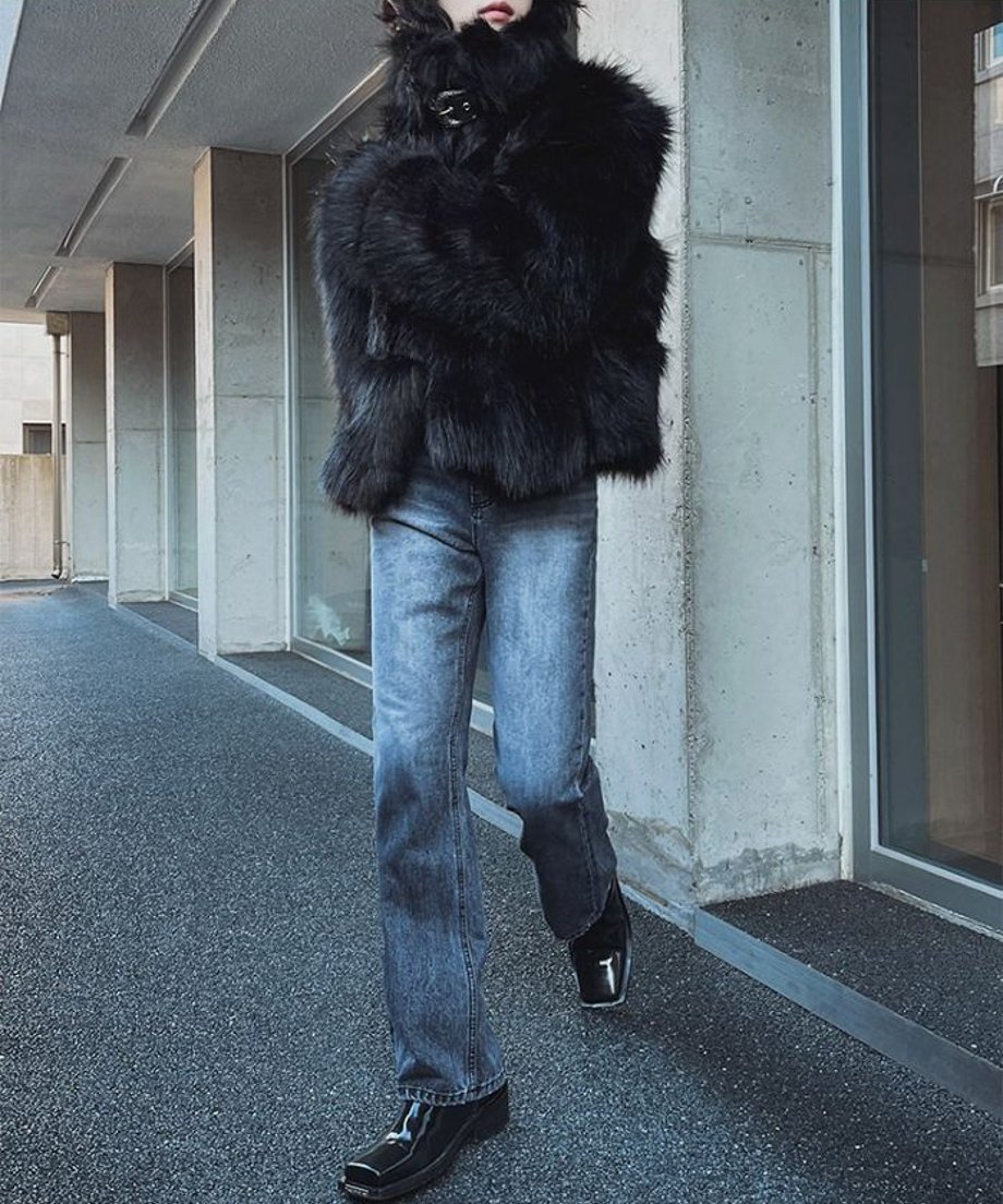 ウォッシュドブルーのワイドデニムパンツにボリュームのある黒のファーコートを羽織り、屋外の通路を歩いている人物の躍動感あるカット