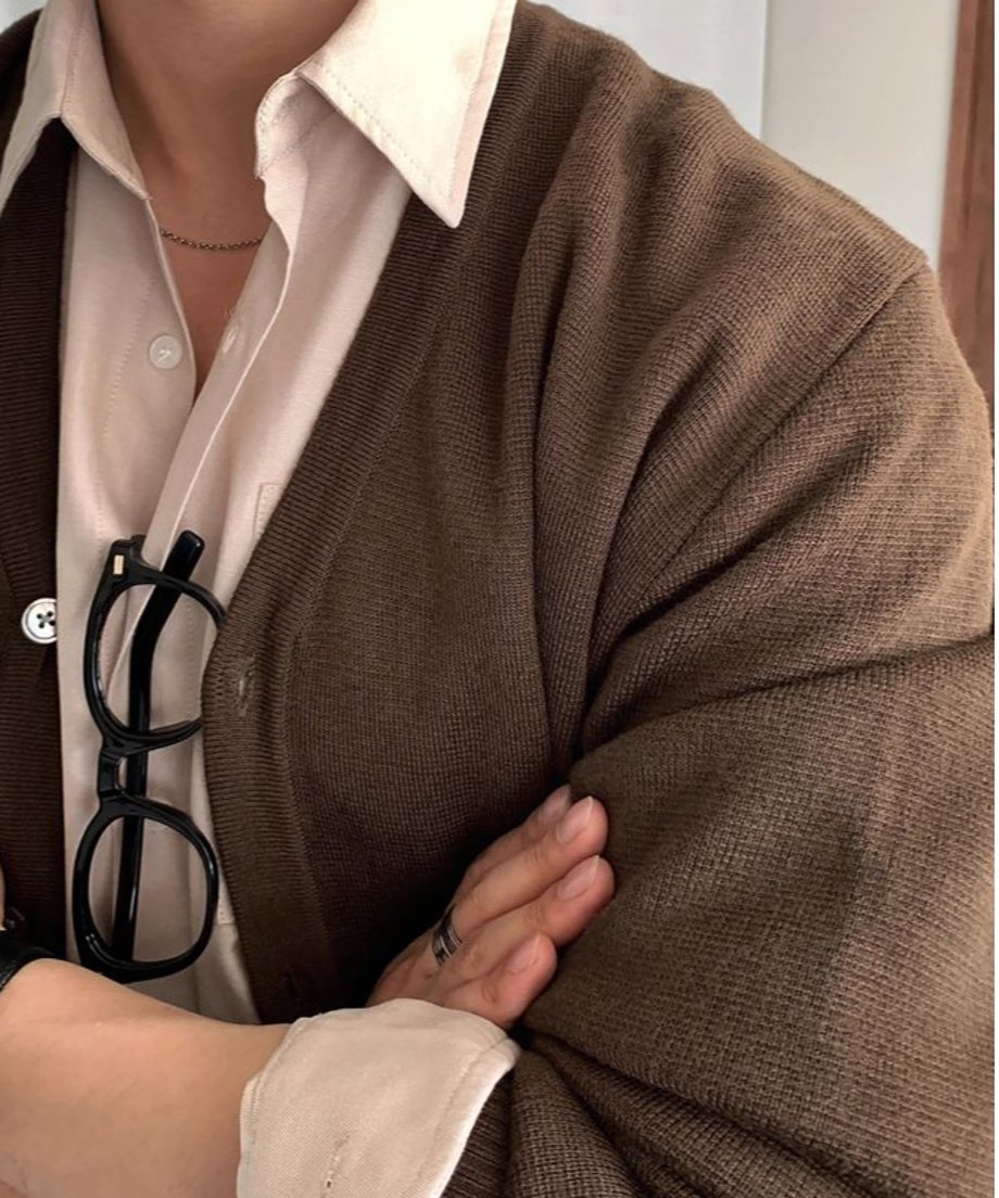 コーヒーカラーのVネックカーディガンを着用した人物の、腕組みをした胸元の超クローズアップカット。